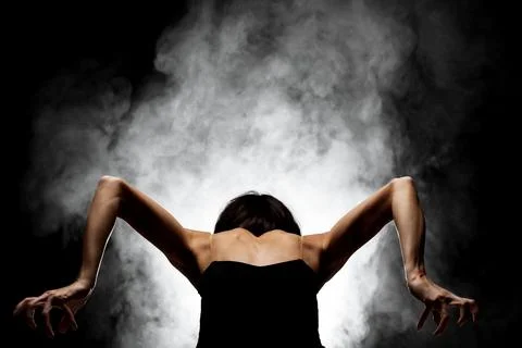 Half silhouette modern ballet dancer posing on dark background with smoke Stock Photos