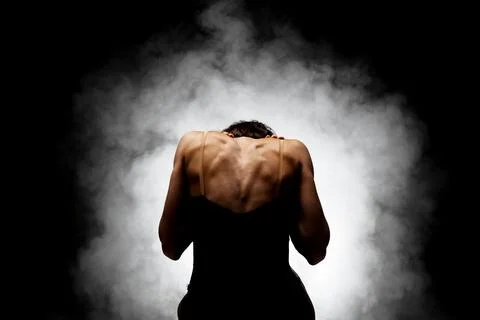 Half silhouette modern ballet dancer posing on dark background with smoke Stock Photos