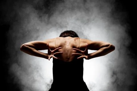 Half silhouette modern ballet dancer posing on dark background with smoke Stock Photos
