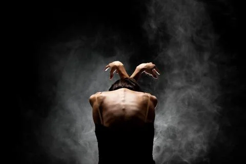 Half silhouette modern ballet dancer posing on dark background with smoke Stock Photos