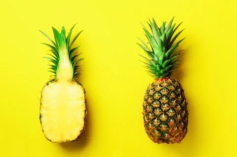 Half slice of fresh pineapple and whole fruit on yellow background. Top View Stock Photos