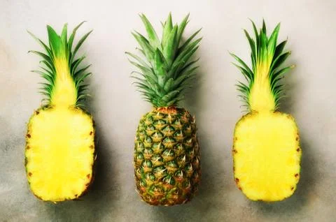 Half slice of fresh pineapple and whole fruit on gray background. Top View. Copy Stock Photos