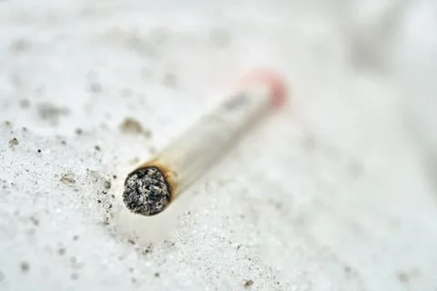Half-smoked cigarette lying on the snow macro photo Stock Illustration