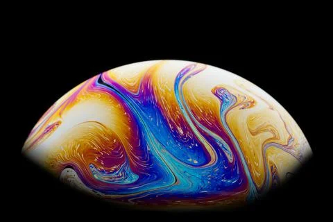 Half a soap bubble on a black background. Rainbow swirl of colors. Stock Photos