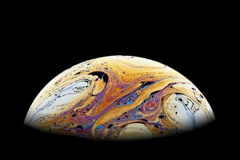 Half a soap bubble on a black background. Bright, beautiful patterns. Stock Photos