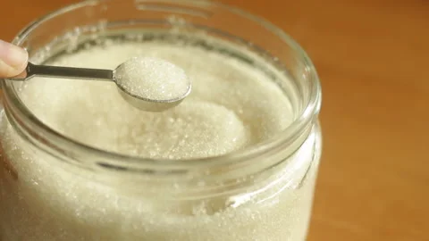 A half teaspoon of white refined sugar cane is being scooped Stock Footage 222697331