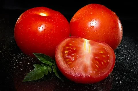 Half the tomato on black background Stock Photos