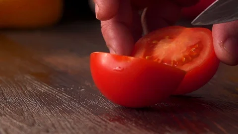 Half a tomato cutting with a knife a vegetable on the board. Chef at work Stockbeeldmateriaal 120305617