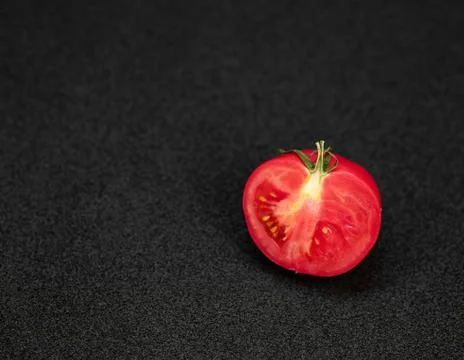 Half a Tomato. Single half of a tomato on a dark background Stock Photos