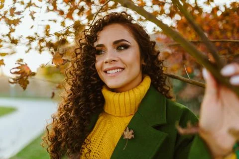 In half-turn to the camera stands a charming curly brunette with a lovely white Stock Photos