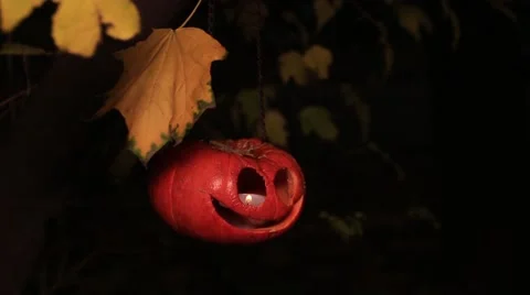 Half-turned jack-o-lantern on a chain with yellow leaves 動画素材 68616493