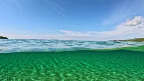 Half underwater slow-motion view of sandy beach bottom, blue sky and clouds Stock-Footage 252284437