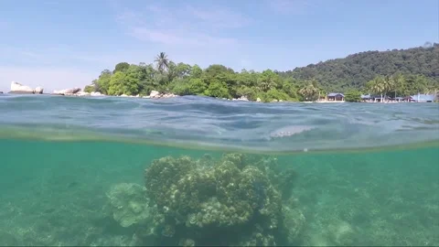 Half water split shot, Corals with Perhentian Island on the background, Malaysia Stock Footage 197575588