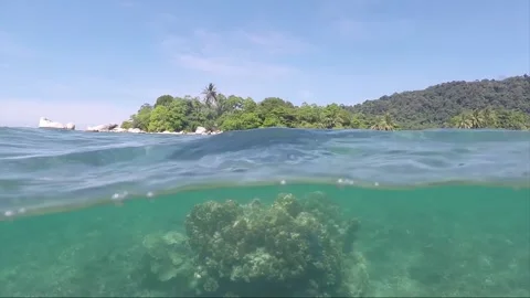 Half water split shot, Corals with Perhentian Island on the background, Malaysia 動画素材 197575652