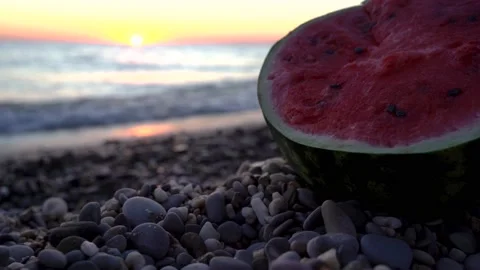 Half a watermelon is lying on the beach with pebbles at sunset. Stock Footage 161805931