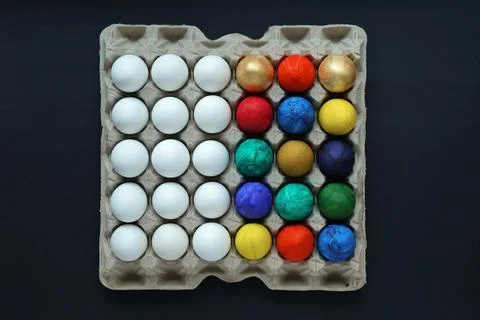 Half white and half colored eggs in square cardboard stand Stock Photos