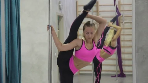 In the hall a bright gymnast performs a vertical twine near the pole. Stock Footage 79577306