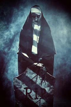 Halloween and Horrors. Devilish evil nun in a cemetery with a tombstone. Myst Stock Photos