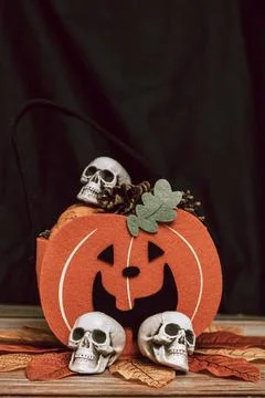 Halloween basket on the table in the shape of a pumpkin, skull and autumn leaves Stock Photos