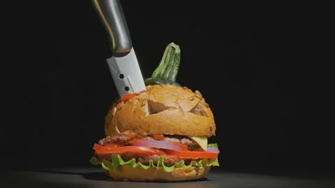 Halloween beef burger in image of pumpkin decorated with knife Video stock 137301958