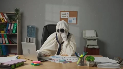 Halloween businessman ghost in white sheet sits at office desk works on laptop Stock Footage 313387066