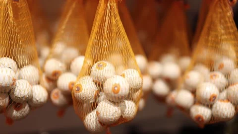 Halloween candy eyeballs in orange mesh bags displayed as creepy seasonal sweets Stock Footage 346305307