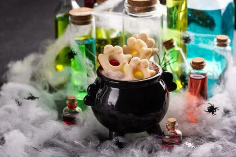 Halloween cauldron filled with ghost shaped cookies surrounded by spooky po.. Stock Photos
