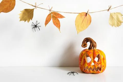 Halloween composition with ceramic pumpkin jack lantern and floral garland on Stock Photos