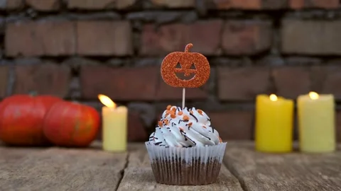 Halloween cupcake. Pumpkin theme with candles on a brick wall background Stock Footage 218198706