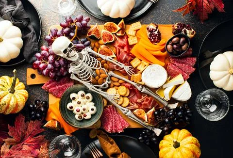Halloween dark  table setting with cheese board decorated with spooky scary s Stock Photos