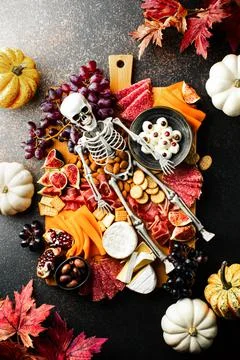 Halloween dark  table setting with cheese board decorated with spooky scary s Stock Photos