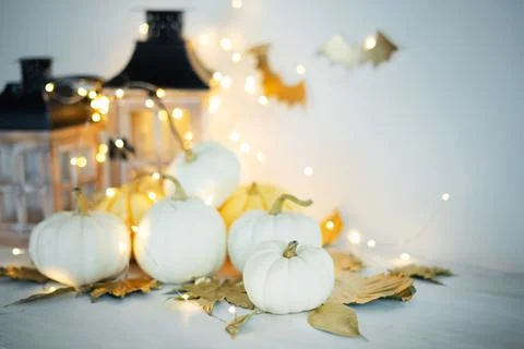 Halloween decor on the table: mini pumpkins, retro lanterns, garlands, golden Stock Photos