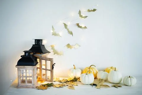 Halloween decor on the table: mini pumpkins, retro lanterns, garlands, golden Stock Photos