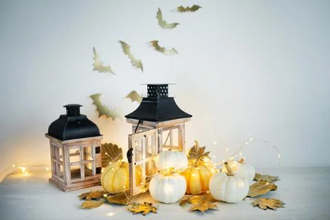 Halloween decor on the table: mini pumpkins, retro lanterns, garlands, golden Stock Photos