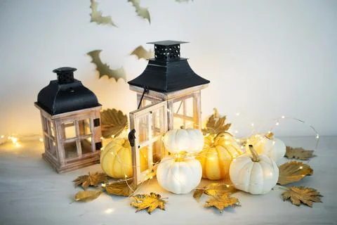 Halloween decor on the table: mini pumpkins, retro lanterns, garlands, golden Stock Photos