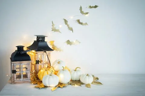 Halloween decor on the table: mini pumpkins, retro lanterns, garlands, golden Stock Photos