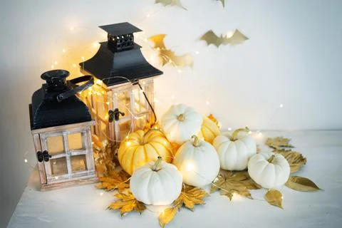 Halloween decor on the table: mini pumpkins, retro lanterns, garlands, golden Stock Photos