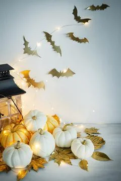 Halloween decor on the table: mini pumpkins, retro lanterns, garlands, golden Stock Photos