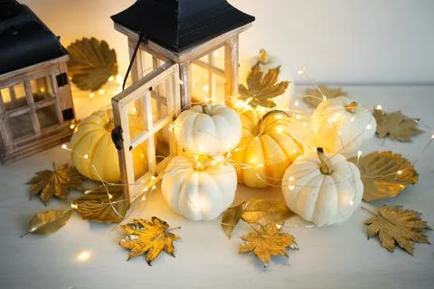 Halloween decor on the table: mini pumpkins, retro lanterns, garlands, golden Stock Photos