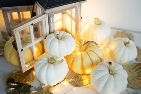 Halloween decor on the table: mini pumpkins, retro lanterns, garlands, golden Stock Photos