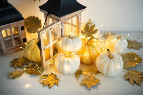 Halloween decor on the table: mini pumpkins, retro lanterns, garlands, golden Stock Photos