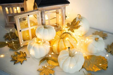 Halloween decor on the table: mini pumpkins, retro lanterns, garlands, golden Stock Photos