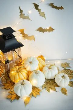 Halloween decor on the table: mini pumpkins, retro lanterns, garlands, golden Stock Photos