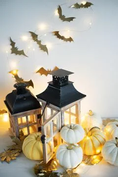 Halloween decor on the table: mini pumpkins, retro lanterns, garlands, golden Stock Photos