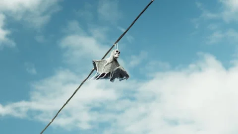 A Halloween decoration hangs from the power lines: a figure of Death in a w.. 動画素材 345147129