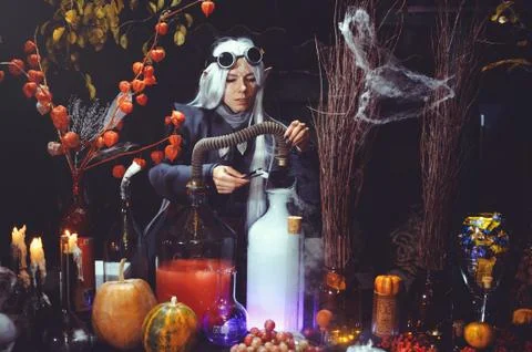 Halloween elf with magic magic in the dark forest. Beautiful young woman in a Stock Photos
