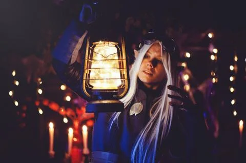 Halloween elf with magic magic in the dark forest. Beautiful young woman in a Stock Photos