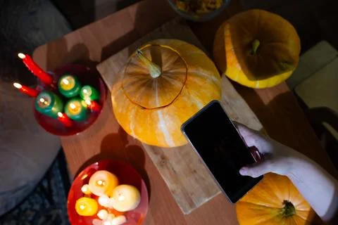 Halloween, Engaging in Pumpkin Carving using a Smartphone in a Cozy and Stock Photos
