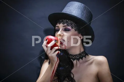 Halloween. Fashion portrait of witch or night vampire woman with red apple. Stock Photos