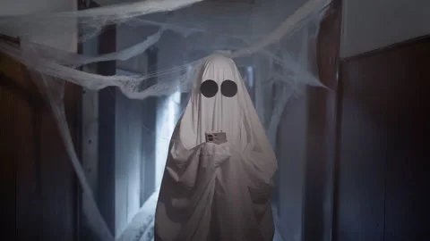 Halloween Ghost surf the Internet uses smartphone, to browse online stores Stock Footage 313554035